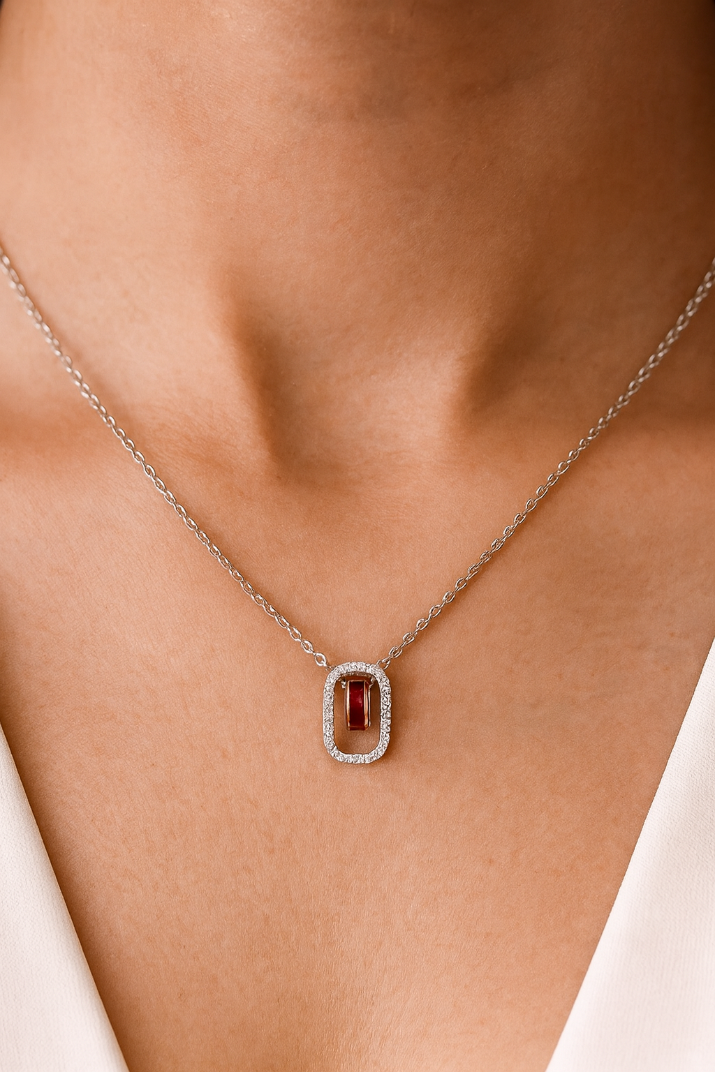 Elegant silver necklace featuring a deep red gemstone framed with sparkling stones