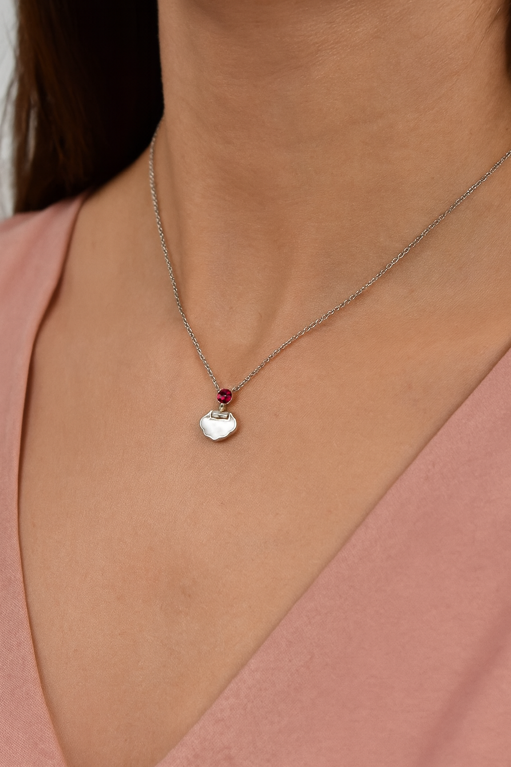 Delicate silver pendant featuring a Ruby gemstone and a sleek charm