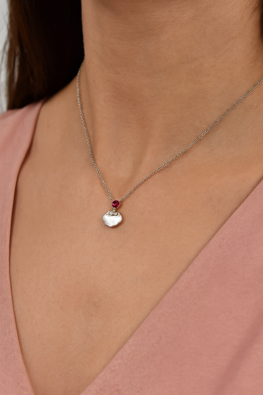 Delicate silver pendant featuring a Ruby gemstone and a sleek charm