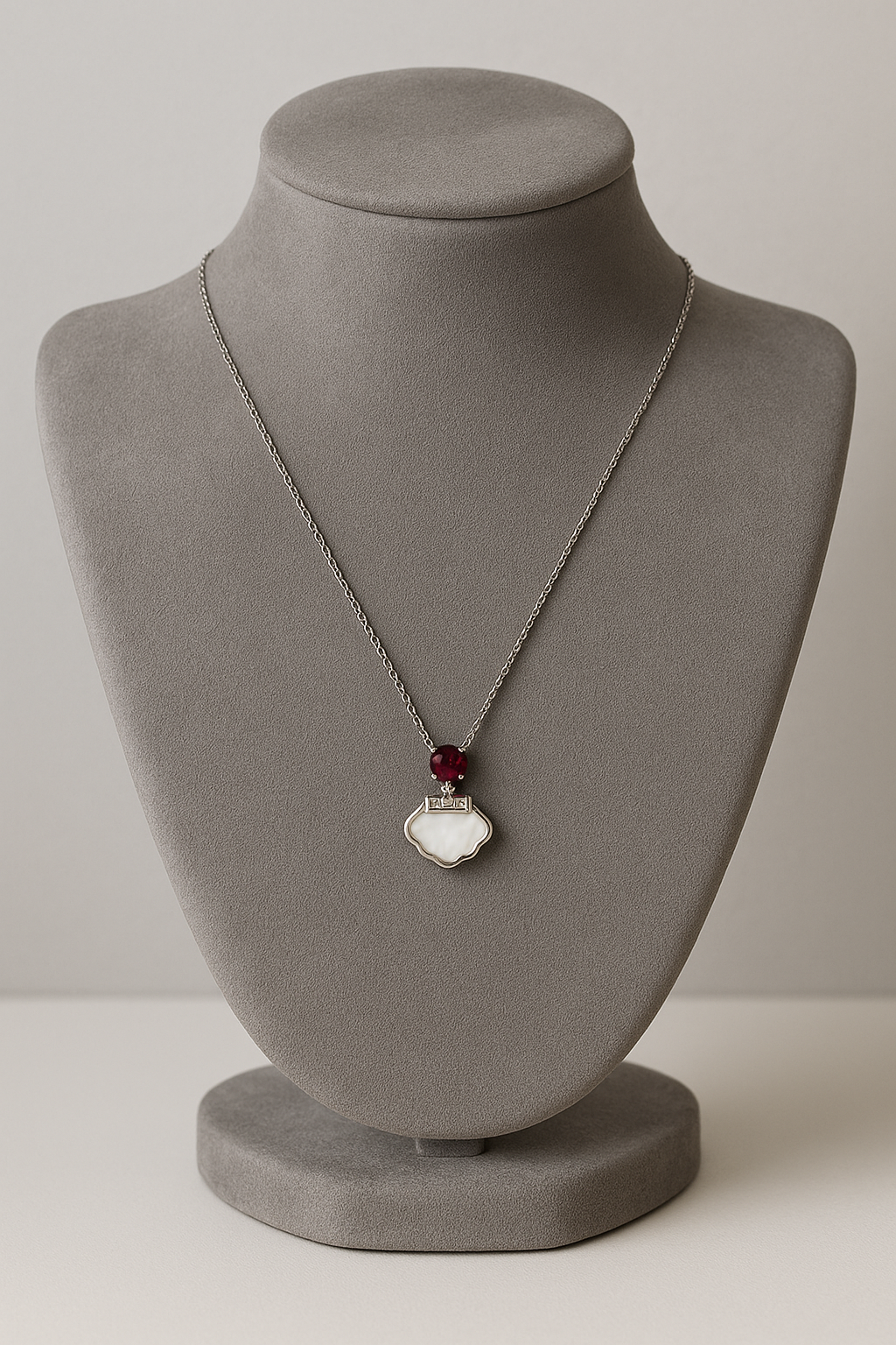 Delicate silver pendant featuring a Ruby gemstone and a sleek charm