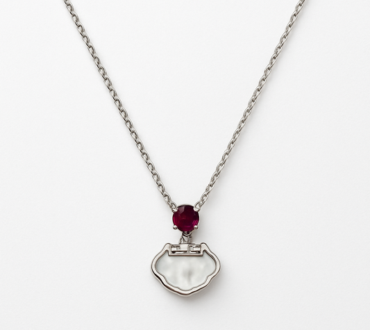 Delicate silver pendant featuring a Ruby gemstone and a sleek charm