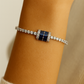 silver tennis bracelet with a bold blue crystal centerpiece