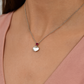 Delicate silver pendant featuring a Ruby gemstone and a sleek charm