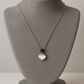 Delicate silver pendant featuring a Ruby gemstone and a sleek charm